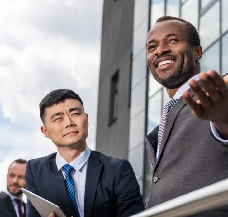 multicultural business team meeting outdoors near office building